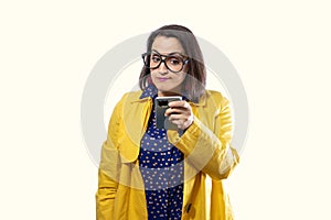 young girl in yellow trench coat looking at cell phone. technology concept