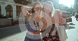 Two young beautiful girls taking selfie on a city street.