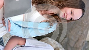 young girls and boy teenager look each other girl looks boy embarrassed holds phone and laptop on big gray stones park