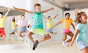 Young girls and boys jumping together in dance room