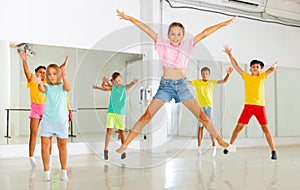 Young girls and boys jumping together in dance room