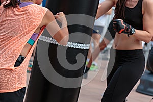 Young Girls doing Fitness and Boxing Workout with Black Punching Bag