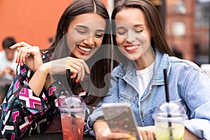 Young girls friends watch something in smartphone.