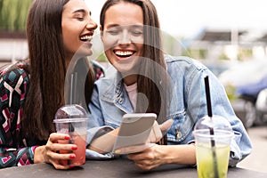 Young girls friends watch something in smartphone.