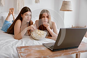 Young girls friends watching funny movie on laptop in bedroom