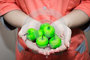 The young girls hand holding a small green Apple. Nutritionist recommends apples