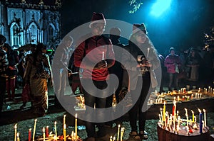 The young girls are praying for Christmas eve with candle lights.