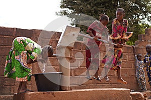 Young Girls Pumping Water At A Public Borehole in West Africa photo