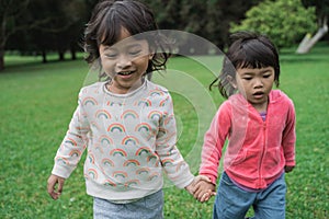 Young girls running together and holding hand in the park