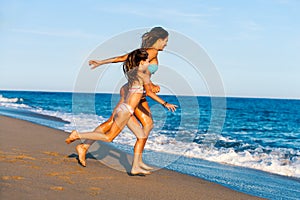 Young girls running towards waves.