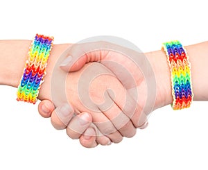 Young girls shaking hands with a bracelet patterned as the rainbow flag. on white