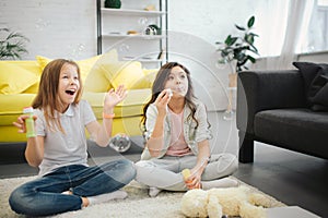 Young girls sitting on floor and having fun. Brunette making luftbolper. Another teenager try to catch them. She rejoice.