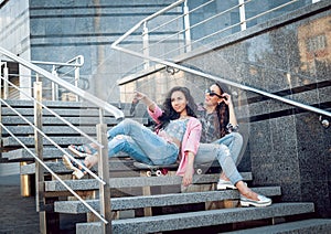 Young girls with skateboard sitting on the stairs