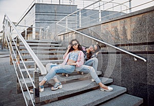 Young girls with skateboard sitting on the stairs