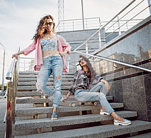 Young girls with skateboard sitting on the stairs