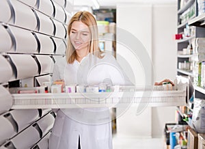 Young glad female customer searching for reliable drug in pharmacy