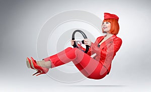 Young glamor girl in red driver car with a wheel