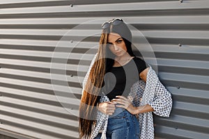 Young glamorous elegant woman in round sunglasses with long hair in a black fashionable t-shirt in a vintage summer jacket