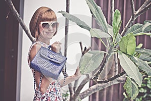 Young glamour woman wearing flower dress posing with luxury handmade snakeskin python handbag. Beautiful stylish girl