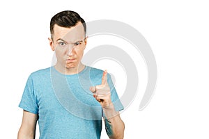 Young gloomy threaten man with a finger, dressed in a blue t-shirt on a isolated white background. Close up portrait