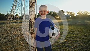 Young goalkeeper with the ball at hand near the goal post.