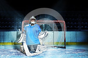 Young goaltender guards his net during hockey game photo