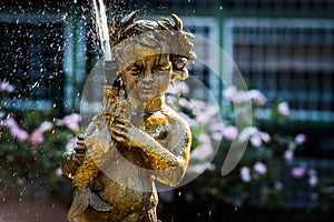 Young golden angel with laurel wreath fishing in his fountain.