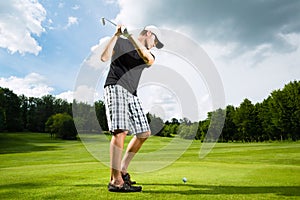 Young golf player on course doing golf swing