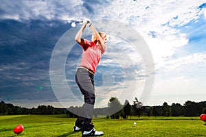 Young golf player on course doing golf swing