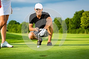 Young golf player on course putting and aiming photo