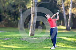 Young golf player hits a driver shot from the tee on a golf course. Concept: competition, concentration, sport, wealthy life.