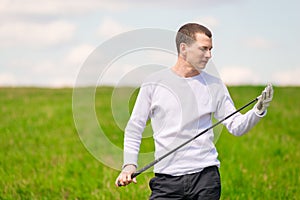 A young golfer examines his golf club before