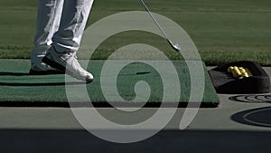 Young golfer practices his golf swing on driving range, view from side