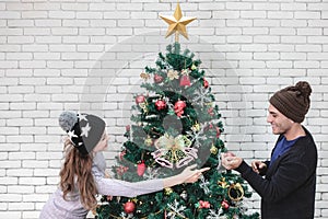 Young good looking Cacausian couple decorate christmas tree together in celebration time.