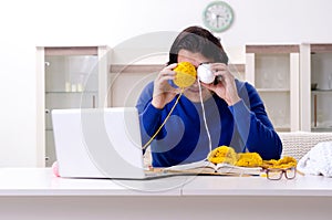 Young good looking man knitting at home