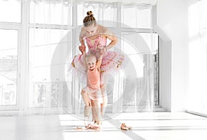 Young gorgeous ballerina with her little daughter dancing in studio