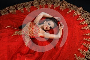 Young gorgeous dreamy woman lying in red dress