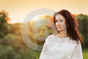 Young gorgeous lady in white dress in sunset beams