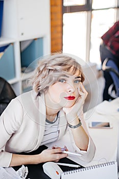 Young gorgeous woman with fair short hair leaning with hand on her chin