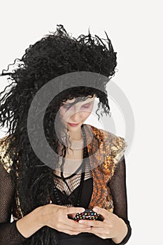 Young Goth woman with teased hair texting on cell phone over gray background