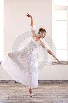 Young graceful ballerina dancing on white studio.