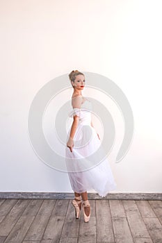 Young graceful ballerina dancing on white studio.