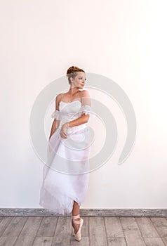 Young graceful ballerina dancing on white studio.