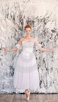 Young graceful ballerina dancing on white studio.