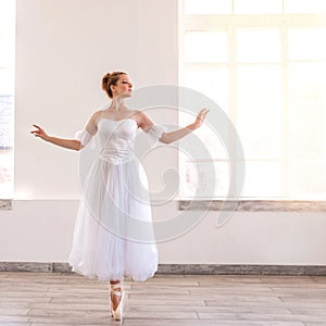 Young graceful ballerina dancing on white studio.