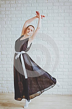 Young and graceful ballerina in pointe shoes and black dress dances in the studio. Choreography and dancing classes concept.