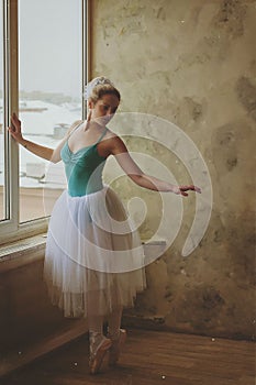 Young and graceful ballerina in pointe shoes and a tutu dances in the studio. Choreography and dancing classes concept.