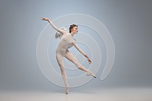 Young and graceful ballet dancer, ballerina dancing in image of angel with wings  on gray studio background. Art