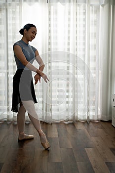 Young graceful ballet dancer in tights and leotard practicing new movement for performance