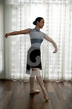 Young graceful ballet dancer in tights and leotard practicing new movement for performance